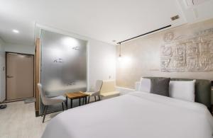 a hotel room with a bed and a table and chairs at Daejeon Yuseong MAC Hotel in Yusŏng