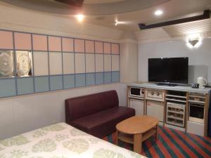 甲府市にあるゴルフ 甲府昭和 (大人専用)のベッド、椅子、テレビが備わる客室です。