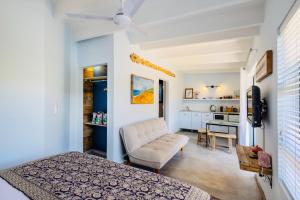 a bedroom with a bed and a chair and a kitchen at The Warren @White.Rabbit.House in Plettenberg Bay