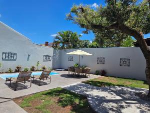 a patio with a table and chairs and an umbrella at Casa Ninhal, super central, nova e espaçosa. in Bonito