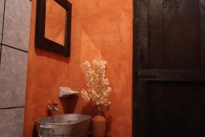 an orange wall with a bucket and a vase of flowers at Villa Xanvil in Zinacantán