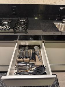 a drawer in a stove with utensils in it at Vertice House - Copacabana in Uberlândia