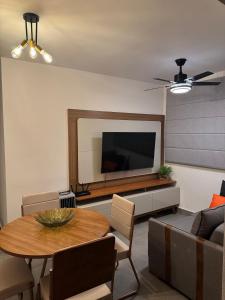 a living room with a table and a flat screen tv at Vertice House - Copacabana in Uberlândia