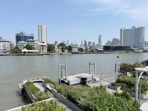 a dock on a river with a city in the background at The Quarter Chaophraya by UHG - Riverfront Hotel, Walk to ICONSIAM in Bangkok