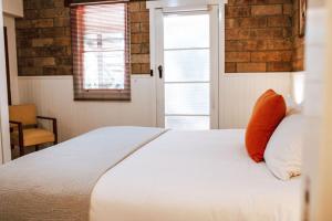a bedroom with a white bed with an orange pillow at Tillrander - Scamander Retreat in Scamander