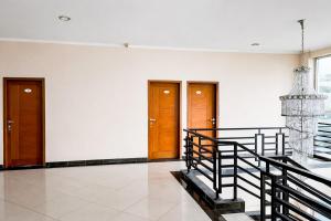 a hallway with two doors and a staircase and a chandelier at RedDoorz Plus near The Great Asia Africa Lembang in Bandung