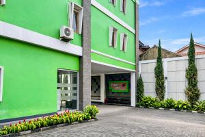 a green and white building with flowers and plants at RedDoorz Plus near The Great Asia Africa Lembang in Bandung