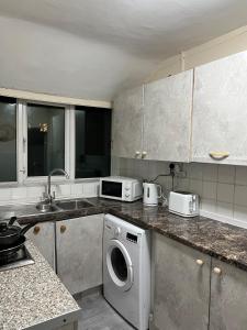 a kitchen with a washing machine and a microwave at House in Manchester - G Escape in Manchester +27 photos
