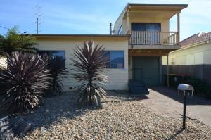 a house with palm trees in front of it at Seahaven Beach House - Shellharbour in Shellharbour