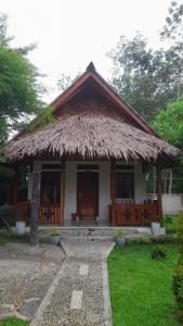 a small building with a straw roof at Leuser Inn & Jungle Trekking in Bukit Lawang