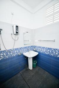 a bathroom with a white sink and blue tiles at Summerland Residence in Udawalawe +39 photos