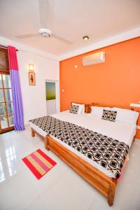 a bedroom with a large bed with an orange wall at Summerland Residence in Udawalawe