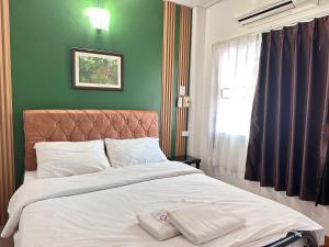 a bed in a bedroom with a green wall at Pakdee House in Udon Thani