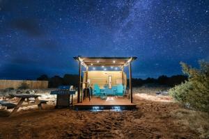 a cabin with a table and chairs under a starry sky at Grand Canyon Stargazing Camper in Williams
