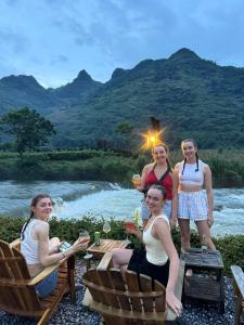 a group of women sitting around a table next to a river at Cheers Ecolodge Du Già in Làng Cac