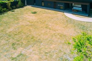 a yard with grass and weeds in front of a building at abrAsus house Fuji in Narusawa
