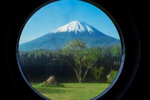 a view of a mountain through a round window at abrAsus house Fuji in Narusawa