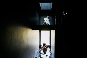 a man sitting in a bed in a room with a window at abrAsus house Fuji in Narusawa +10 photos