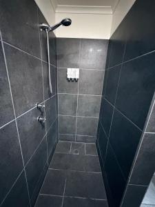 a bathroom with a shower with black tiles at Jerilderie Motor Inn in Jerilderie +38 photos