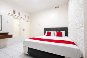 a white bedroom with a large bed with red pillows at RedDoorz Syariah at Cimahi in Cimindi