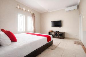 a bedroom with a large bed and a flat screen tv at RedDoorz Syariah at Cimahi in Cimindi