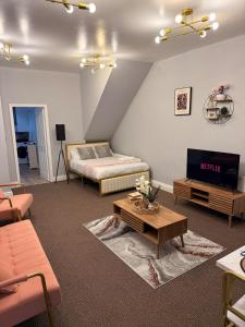a living room with a bed and a tv at Studio Aurelia - Oldham city centre in Oldham