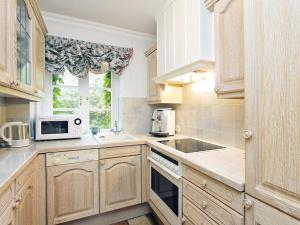 a kitchen with wooden cabinets and a microwave at Heidehaus in Kampen