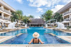 a woman in a hat sitting in the swimming pool at a resort at Centara Kata Resort Phuket in Kata Beach