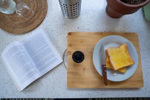 a sandwich on a plate on a cutting board with a book at Villa Ceria Dukuh in Timuran