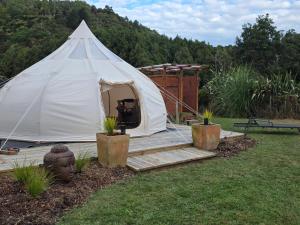 a white tent with a wooden deck in a yard at Blue Aster Retreat in Mokau