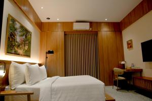 a hotel room with a white bed and a desk at Villa Ceria Dukuh in Timuran