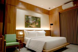 a bedroom with a bed and a green chair at Villa Ceria Dukuh in Timuran