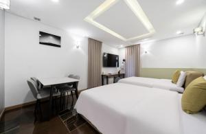 a hotel room with two beds and a desk at Daejeon Yuseong MAC Hotel in Yusŏng