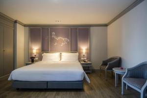 a bedroom with a large bed and two chairs at The Pantip Hotel Ladprao Bangkok in Bangkok