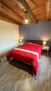 a bedroom with a red bed in a room with wooden ceilings at Le bourg in Vaulry