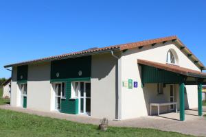 a small white building with green windows and a roof at La vauloube in Châteauponsac