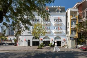 a woman in a white dress standing in front of a building at Paul Chabot Hotel in Hai Phong