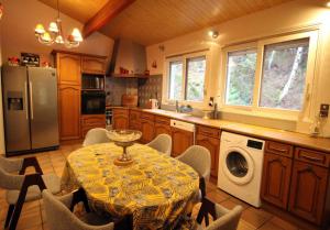 a kitchen with a table and a refrigerator and a dishwasher at Villa du lac in Bujaleuf