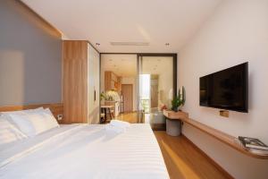 a bedroom with a white bed and a flat screen tv at Anora Home by BRIO in Danang