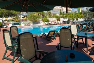 - Piscina con sillas, mesas y sombrilla en Hotel Concordia 3S, en Bibione