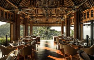 ein Esszimmer mit Tischen und Stühlen und Fenstern in der Unterkunft Four Seasons Resort Koh Samui in Mae Nam