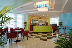 un ristorante con bar con sedie rosse e pavimento a scacchi di Hotel Concordia 3S a Bibione