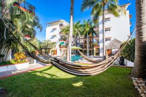 a hammock in a resort yard with palm trees at Gorgeous Penthouse across from Beach with Ocean Views! in Punta Mita
