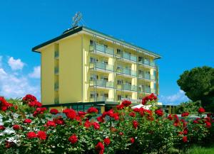 a yellow building with red flowers in front of it at Hotel Concordia 3S in Bibione