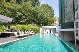 a swimming pool with chairs and a building at Damas Suites & Residences Kuala Lumpur in Kuala Lumpur