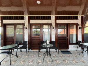 a patio with tables and chairs and windows at Sea Sky Dreams in Kuta Lombok