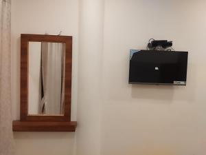 a mirror and a television on a wall at Hotel Alankar in Kanyakumari +28 photos