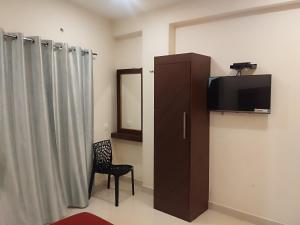 a room with a tv and a chair and curtains at Hotel Alankar in Kanyakumari