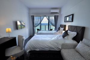 a bedroom with a bed and two chairs and a window at Beach Front Tower Mihama by DSH in Chatan