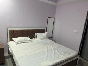 a bed with white sheets and pillows in a room at Hotel Anusuiya palace in Lucknow